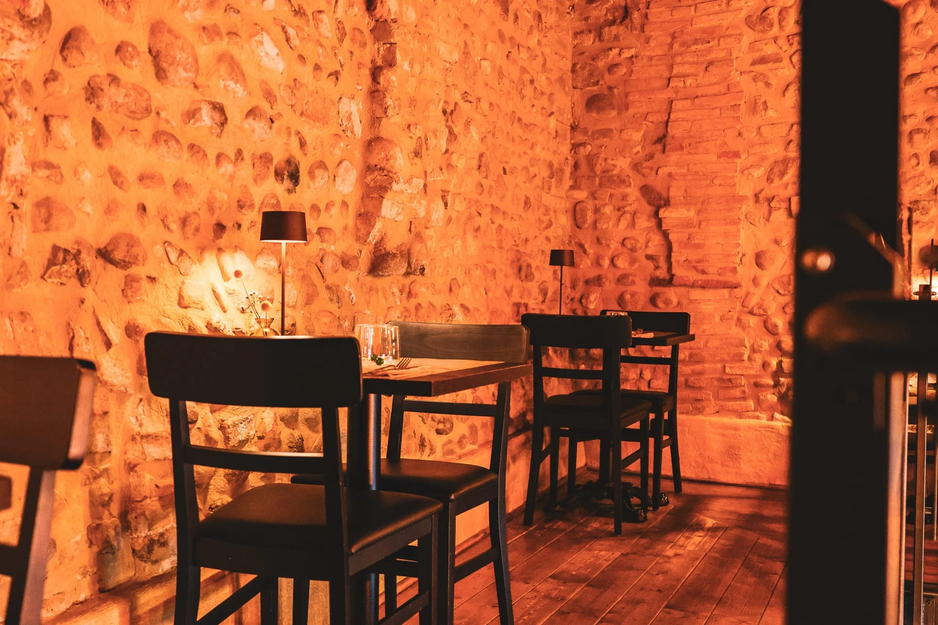 La sala con le pareti in pietra a vista di T'S WAY, pronta per la serata